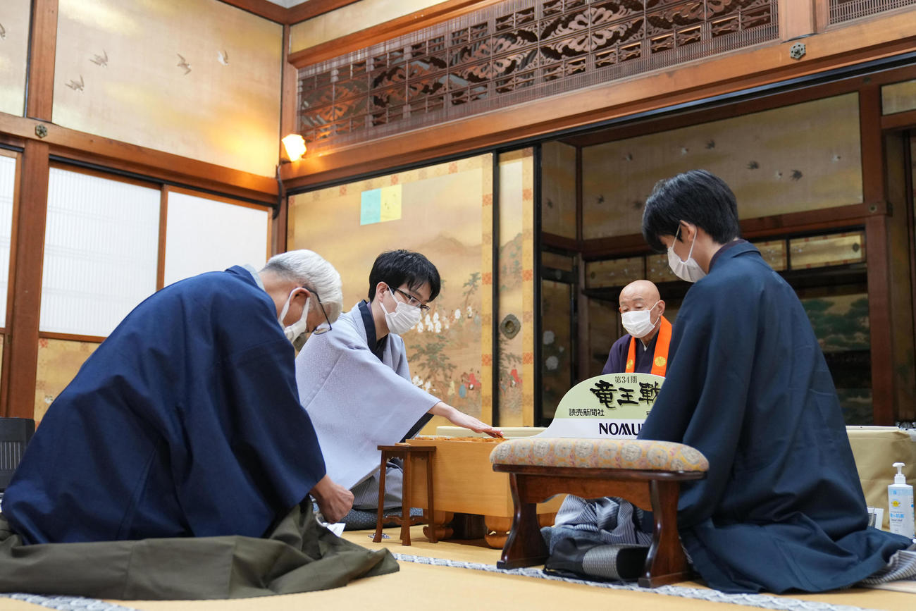 「封じ手」を指す豊島将之竜王（左から2人目）と藤井聡太三冠（右）