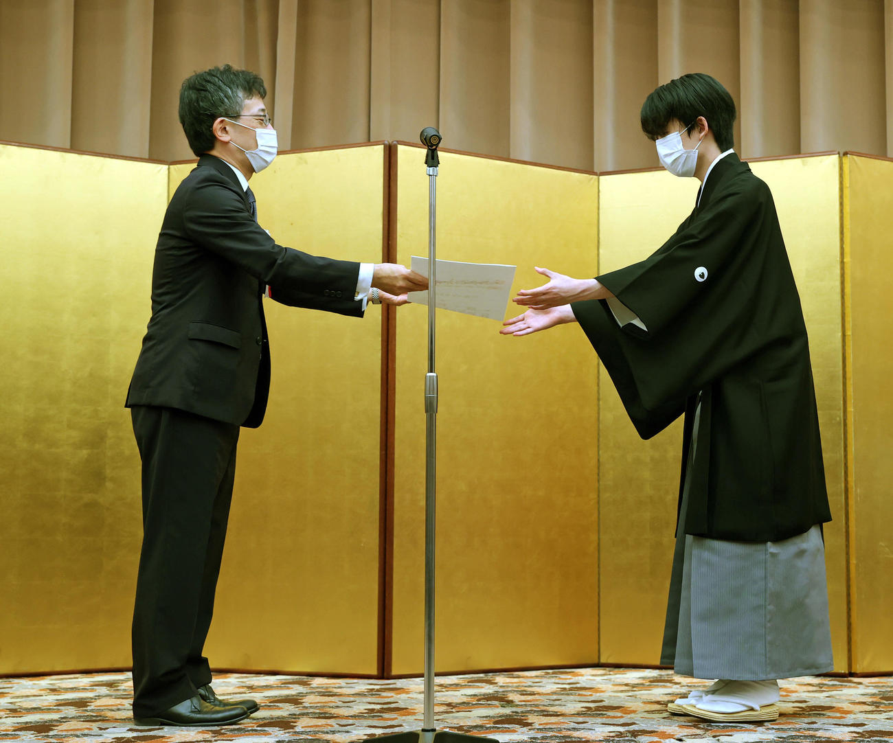 就位状を受け取る藤井聡太王位。左は日本将棋連盟の佐藤康光会長（代表撮影）
