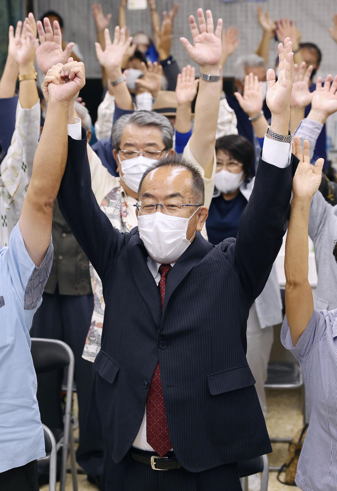 沖縄4区で当選を決め、万歳する自民党の西銘恒三郎沖縄北方相（共同）