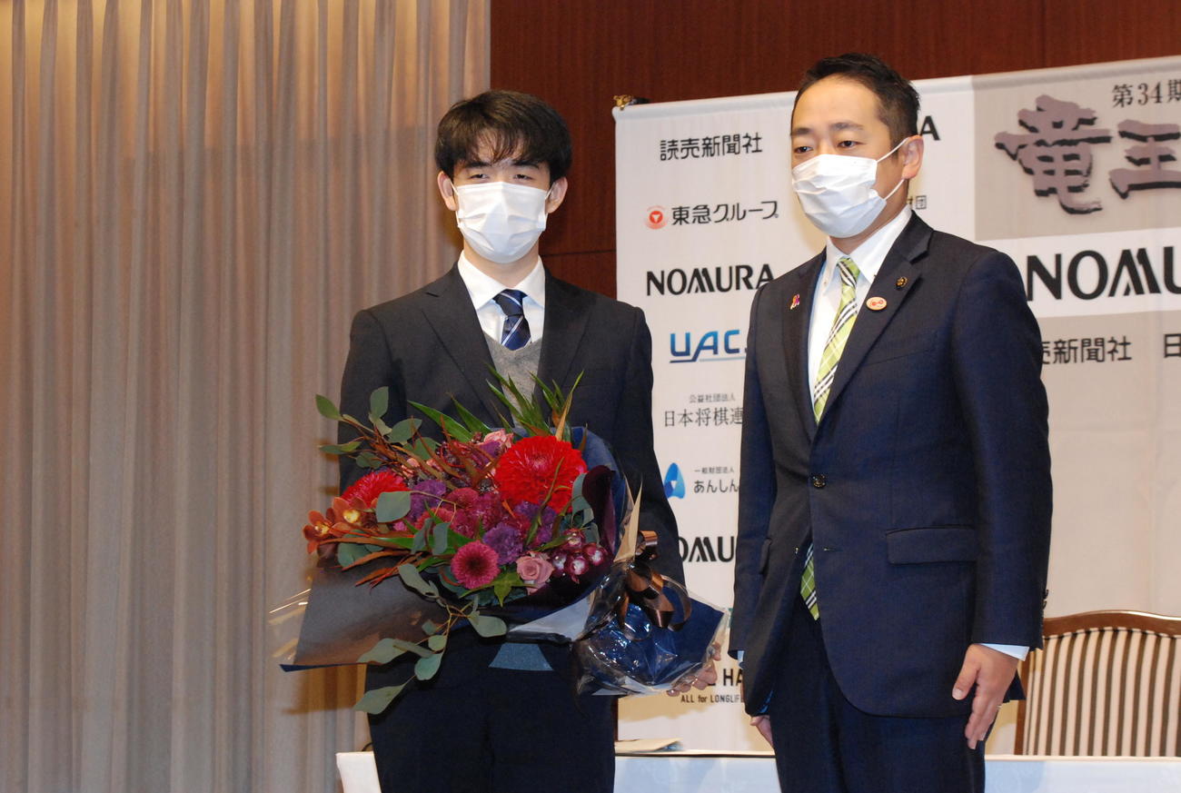 最年少4冠達成から一夜明け会見で篠﨑圭二宇部市長から花束を贈呈される藤井聡太新竜王（撮影・松浦隆司）