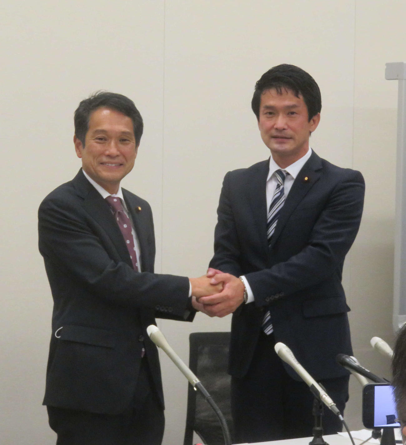 小川淳也元総務政務官（右）で出馬を一本化し、支持を表明した串博志役員室長ががっちり握手を交わした（撮影・大上悟）