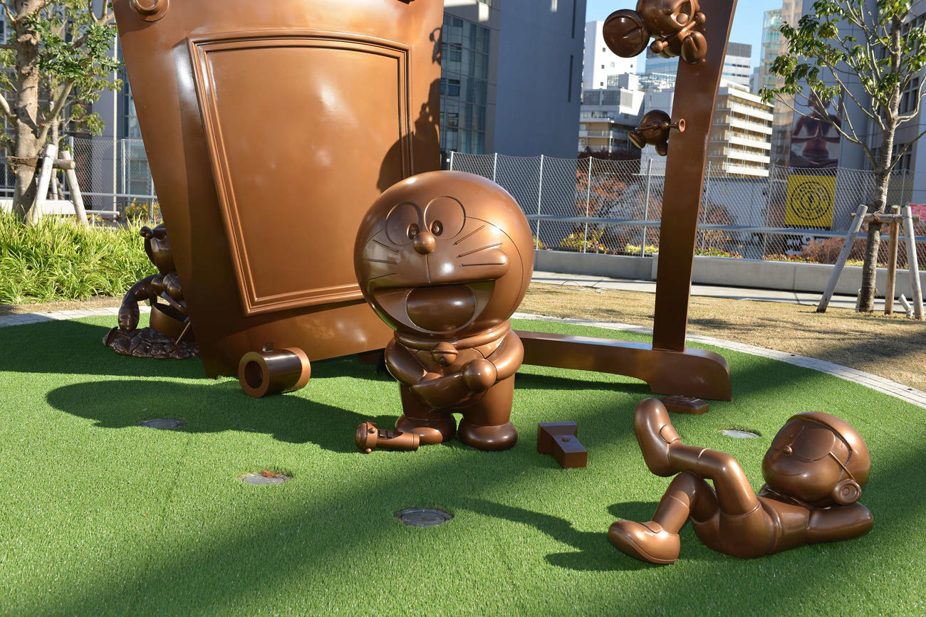 東京・渋谷の宮下公園でお披露目された「ドラえもん」50周年を記念した記念モニュメント「ドラえもん　みらいのとびら」。右は寝転がる野比のび太