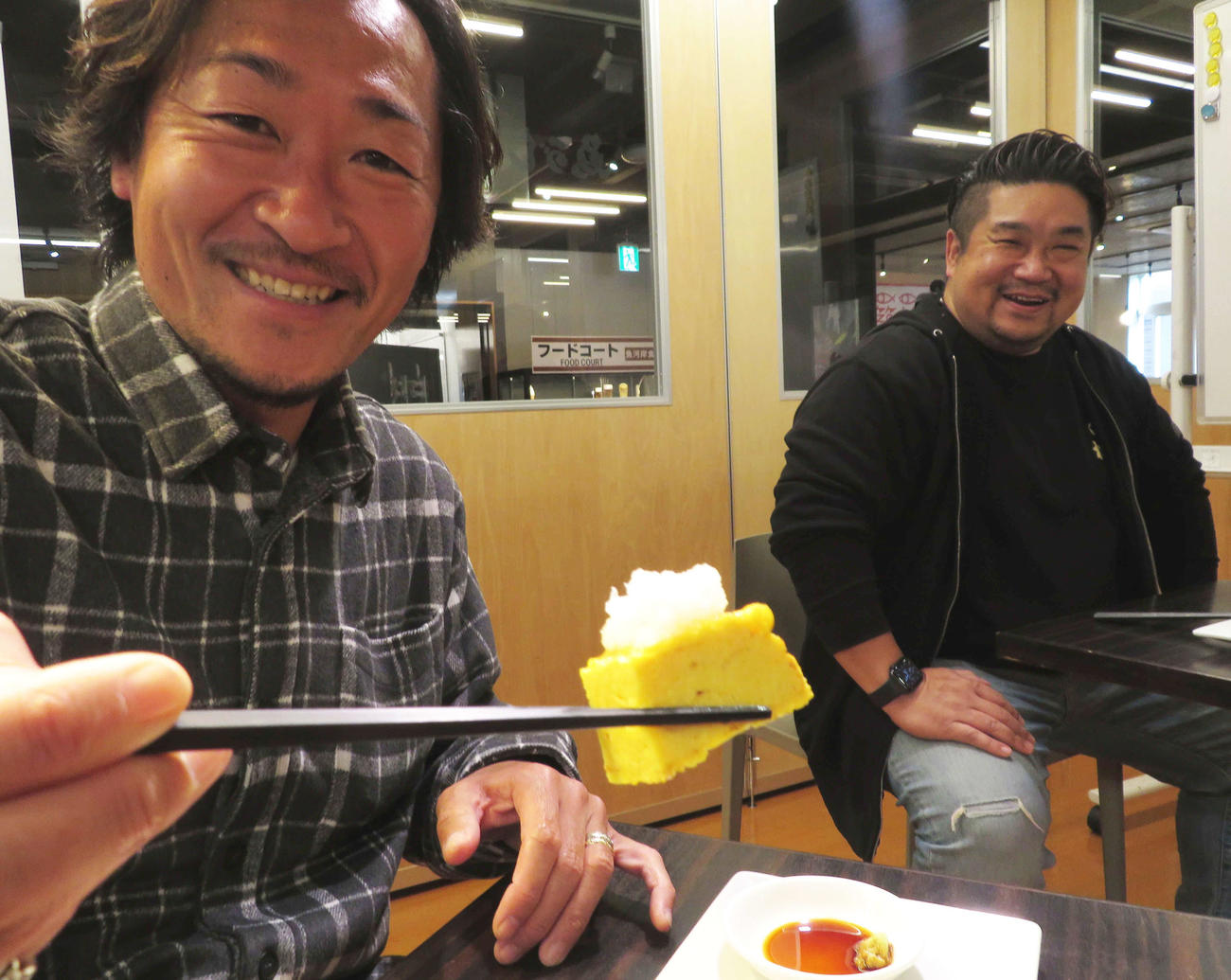 つきぢ松露の玉子焼きに大根おろしをのせ食す石川さん。右はつきぢ松露の斎藤賢一郎社長（撮影・寺沢卓）