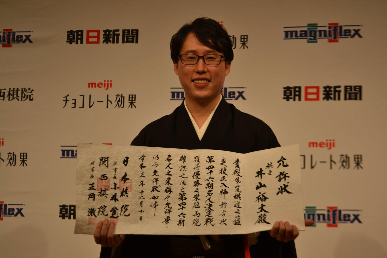 就位式で允許（いんきょ）状を手にする井山裕太名人