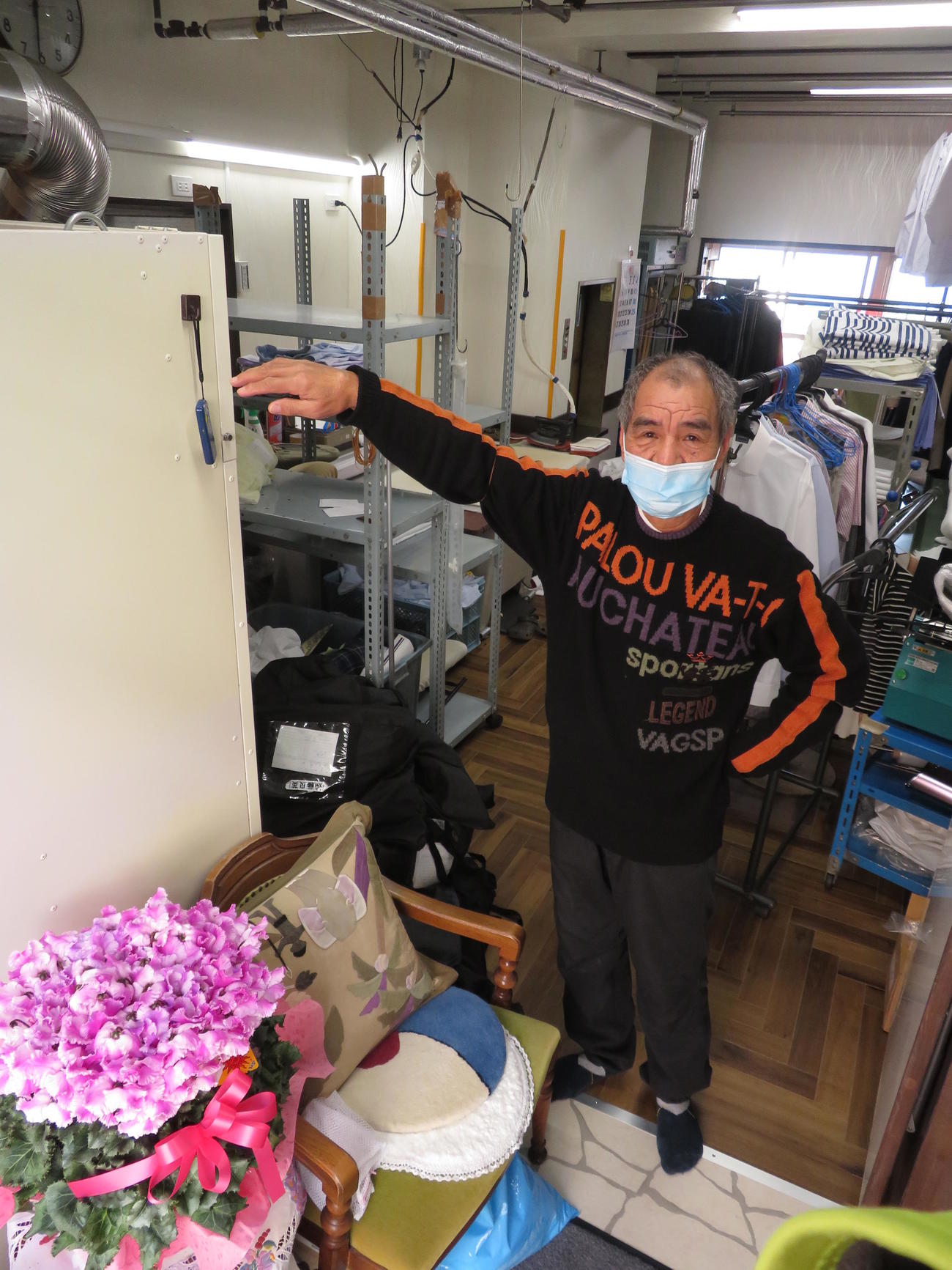 「木むら」隣のクリーニング店で、「流れ込んだ土砂はこのぐらいだった」と示す岡本政夫代表（撮影・寺沢卓）