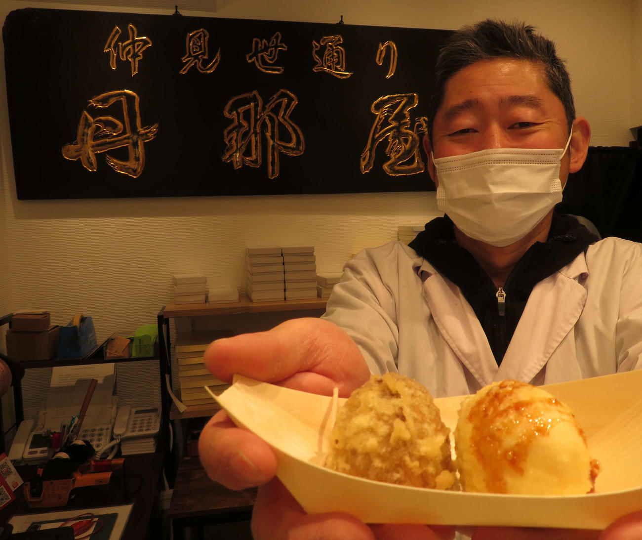 熱海「丹那屋」では、和風スイーツとして出した新商品「まんじゅうの天ぷら」が大ヒット。笑顔の磯聖幸店主と後方はリニューアルオープンを機に掲げた倉庫に眠っていた看板（撮影・寺沢卓）