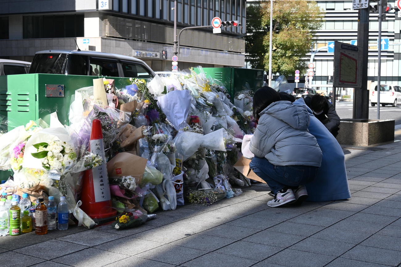 事件発生から2週間、火災現場で手合わせる人の姿は絶えない（撮影・松浦隆司）