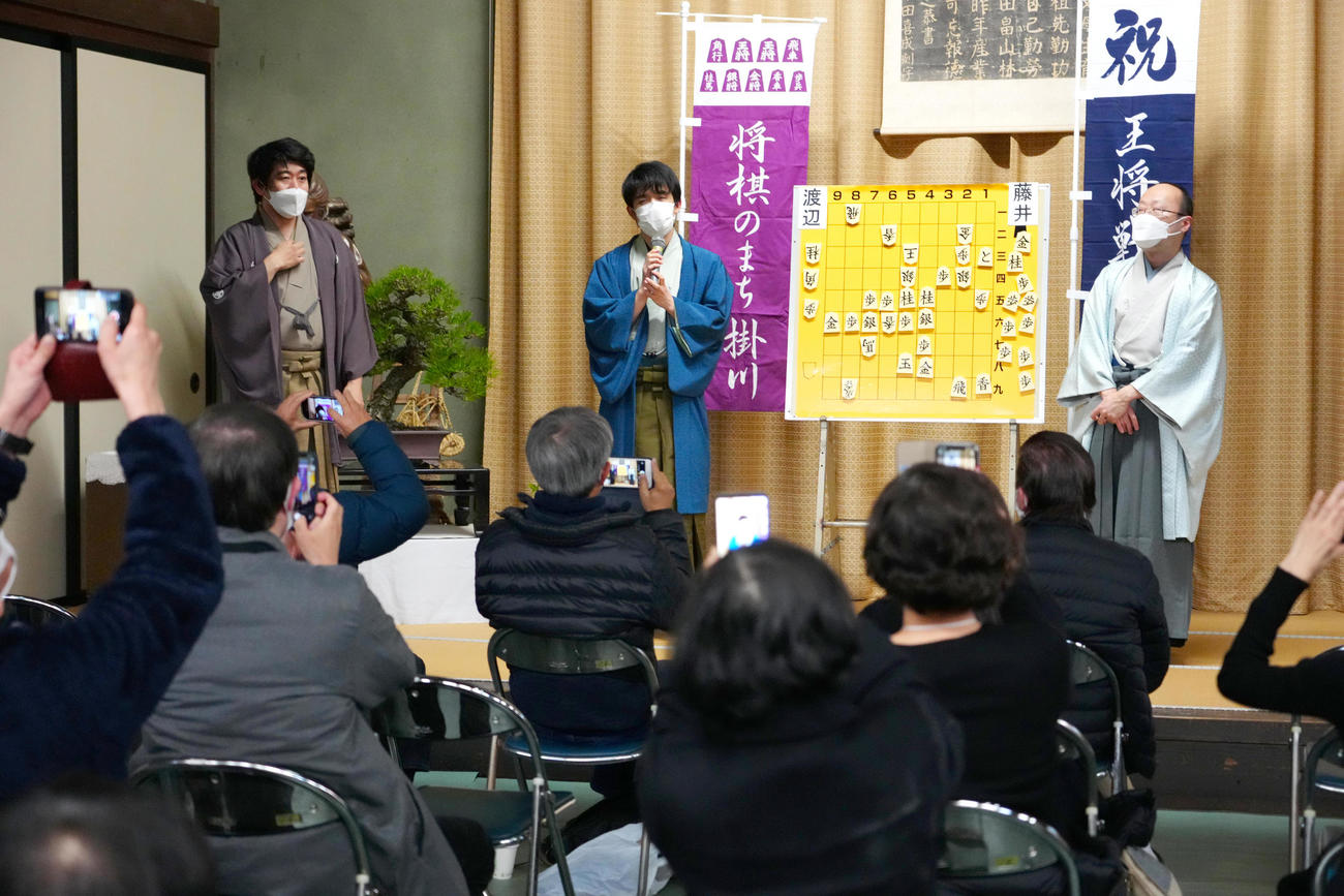 渡辺明王将（右）との王将戦七番勝負第1局の対局を終え、大盤解説会場であいさつする藤井聡太竜王（中央）（代表撮影）