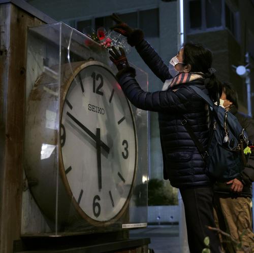 阪神大震災から27年となり、発生時刻で止まったままの大時計に花を手向ける女性（共同）