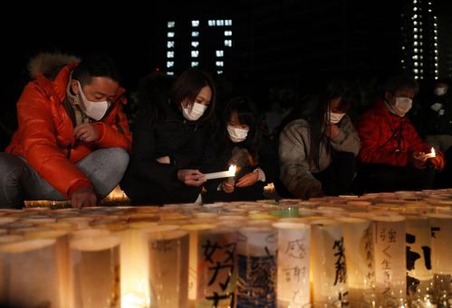 阪神大震災から27年となり、追悼会場で紙製の灯籠に灯をともす人たち（共同）