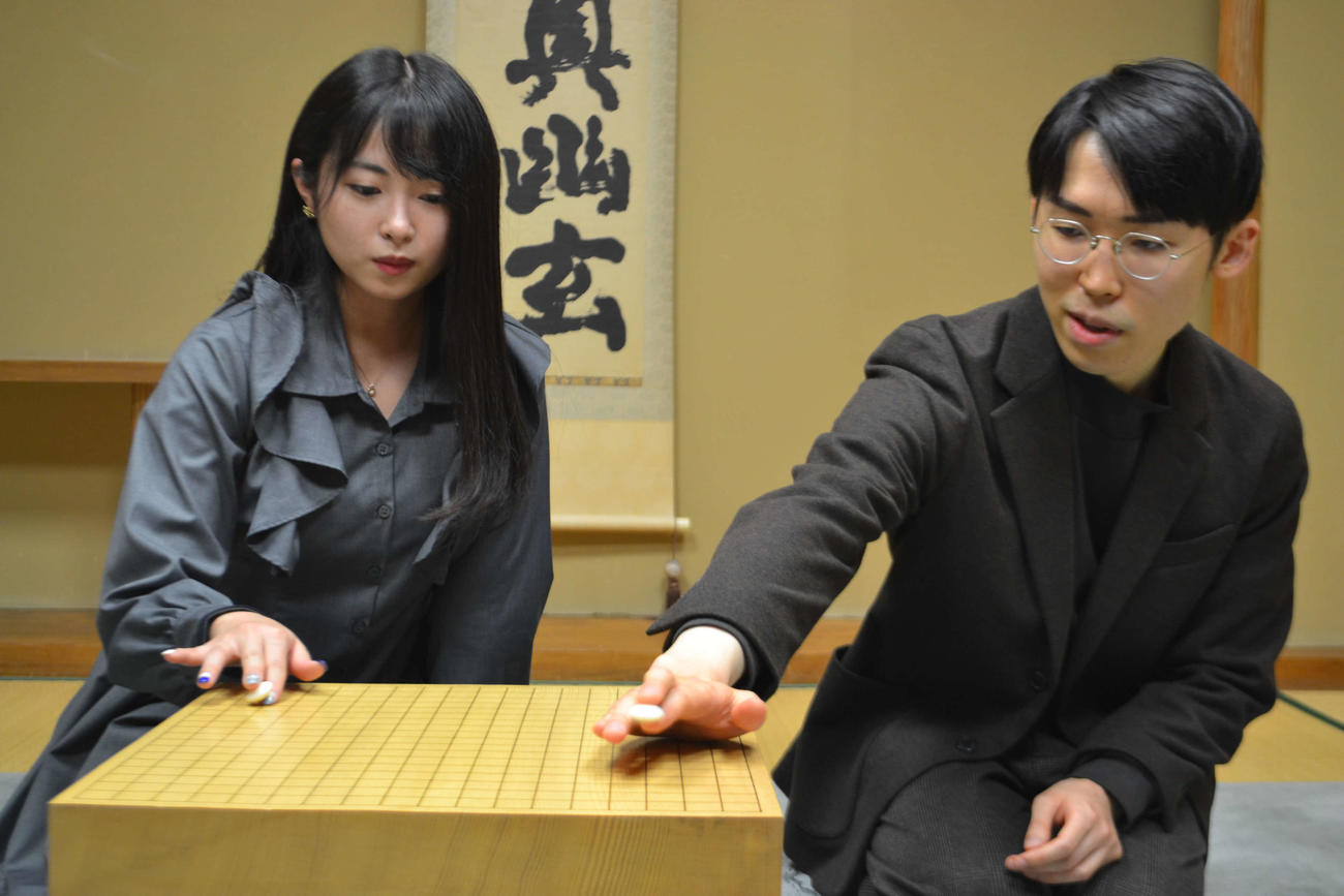 外柳四段（右）に碁石の持ち方を教えてもらう佐藤望美