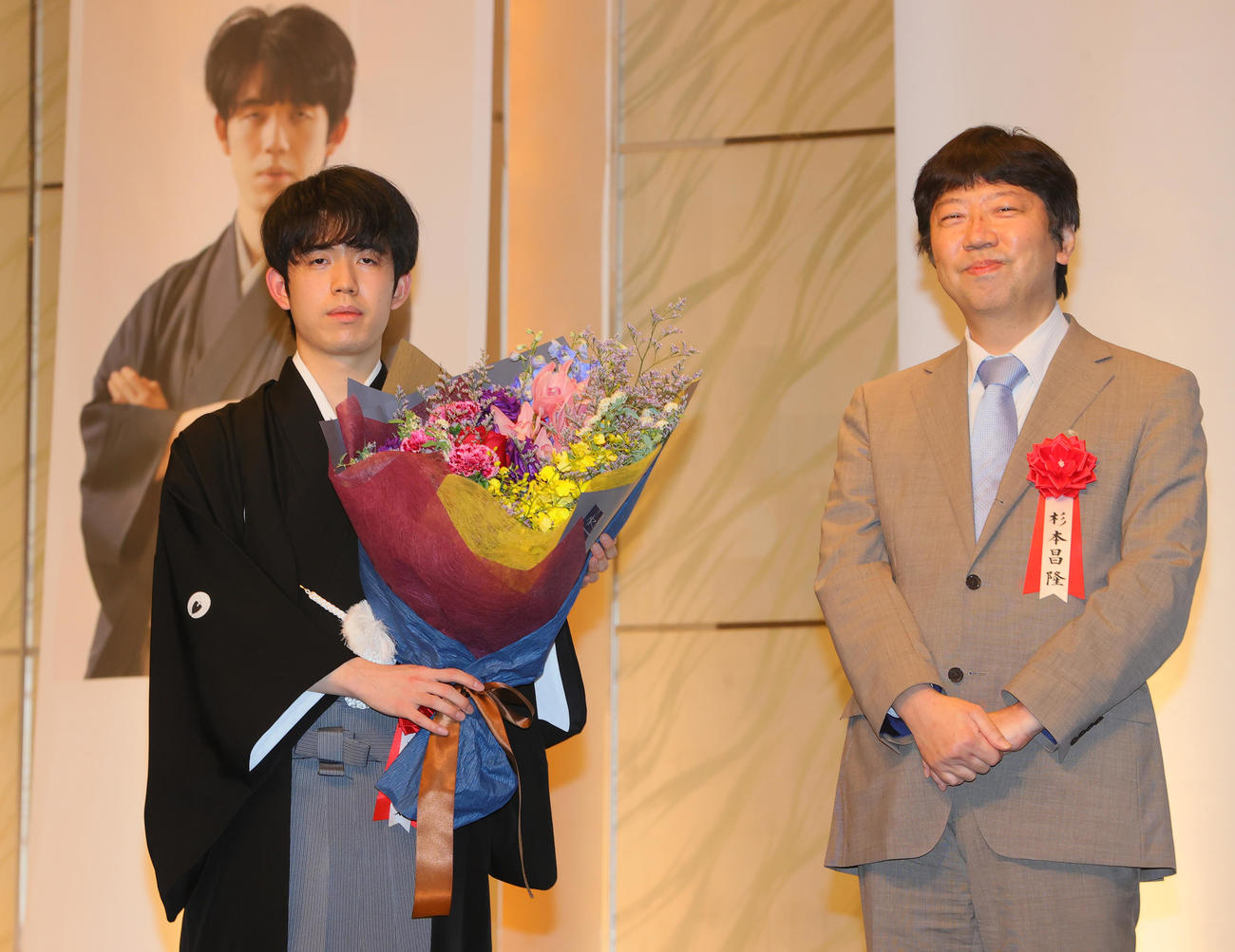 第34期竜王就位式で師匠の杉本八段（右）から花束を受け取る藤井竜王（撮影・野上伸悟）