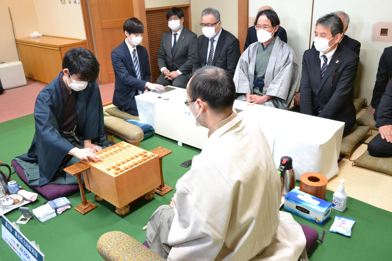 第3局の初手を指す先手の藤井聡太竜王（左、日本将棋連盟提供）