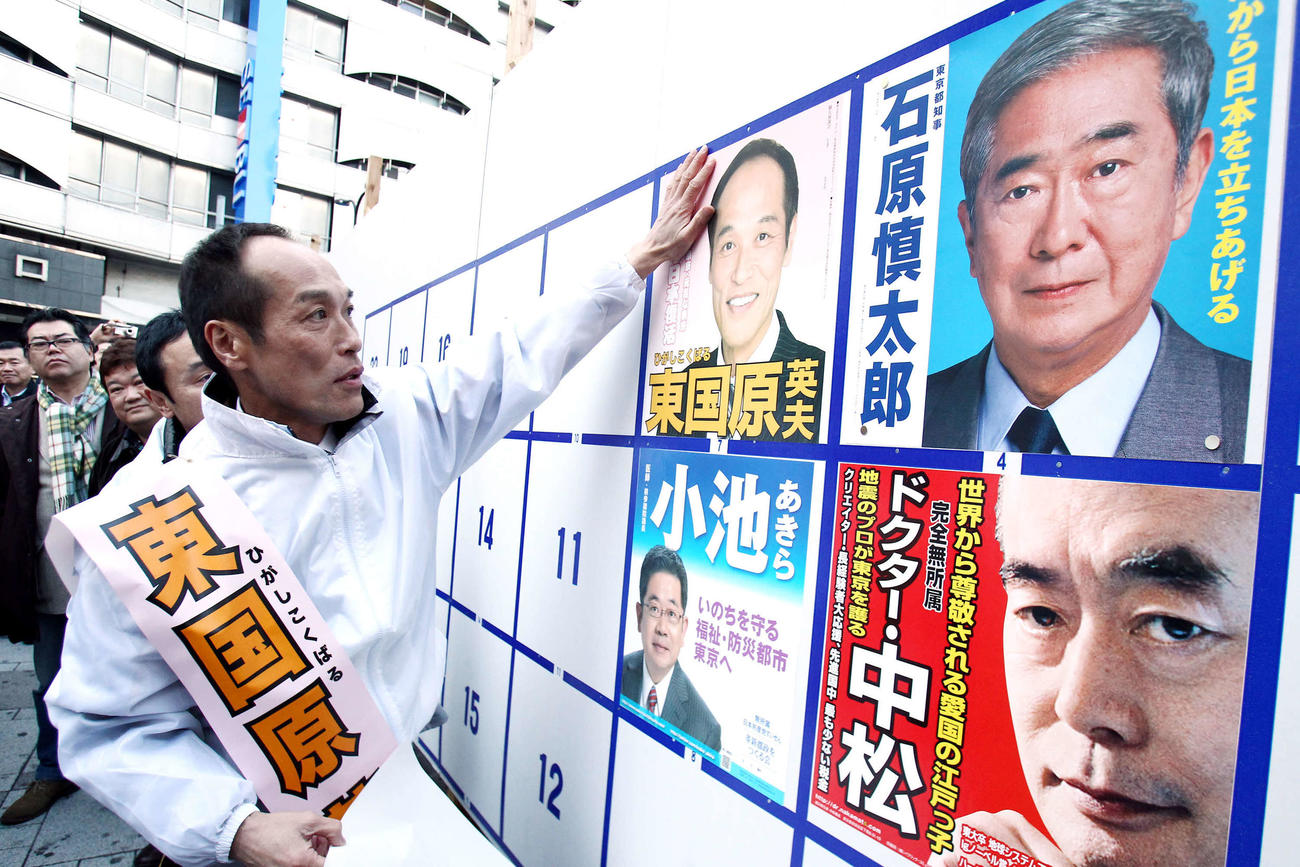 東京都知事選告示で、池袋駅前で演説を終えた東国原英夫氏は選挙公示のポスターを自ら張る。隣には石原慎太郎現知事のポスターが（2011年3月24日撮影）