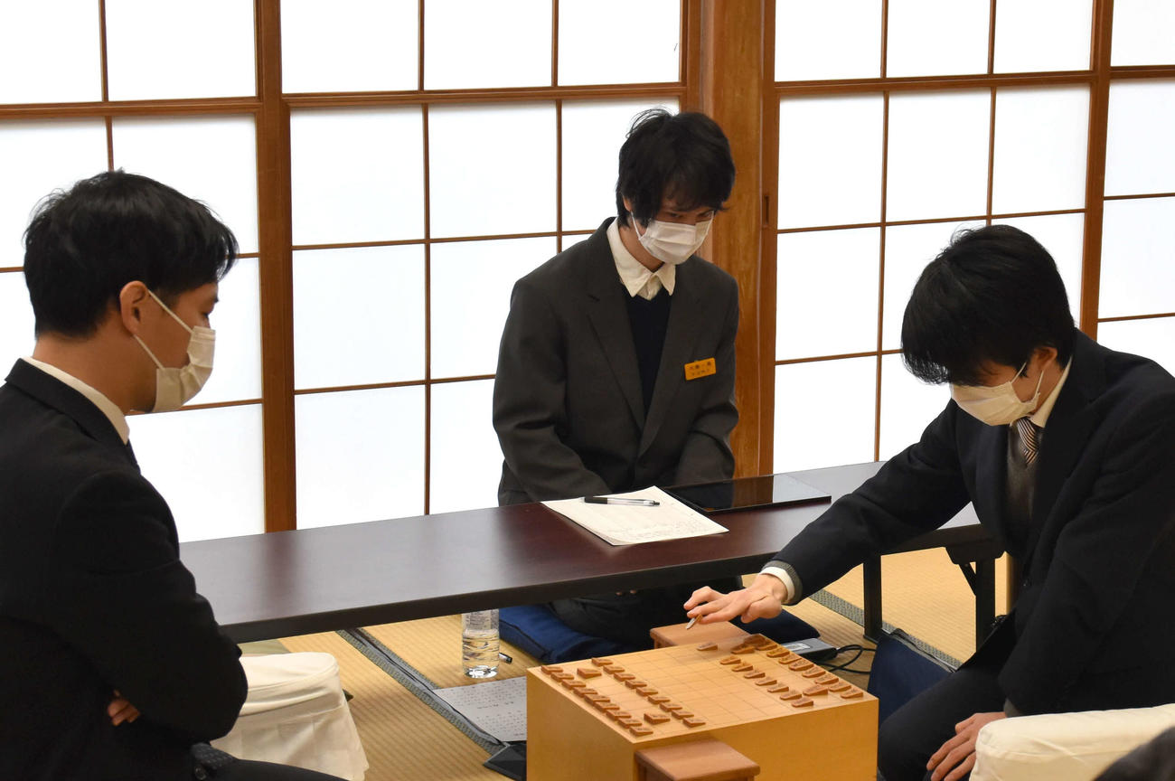 順位戦B級1組の阿久津主税八段（左）戦で初手を指す藤井聡太竜王（右、日本将棋連盟提供）