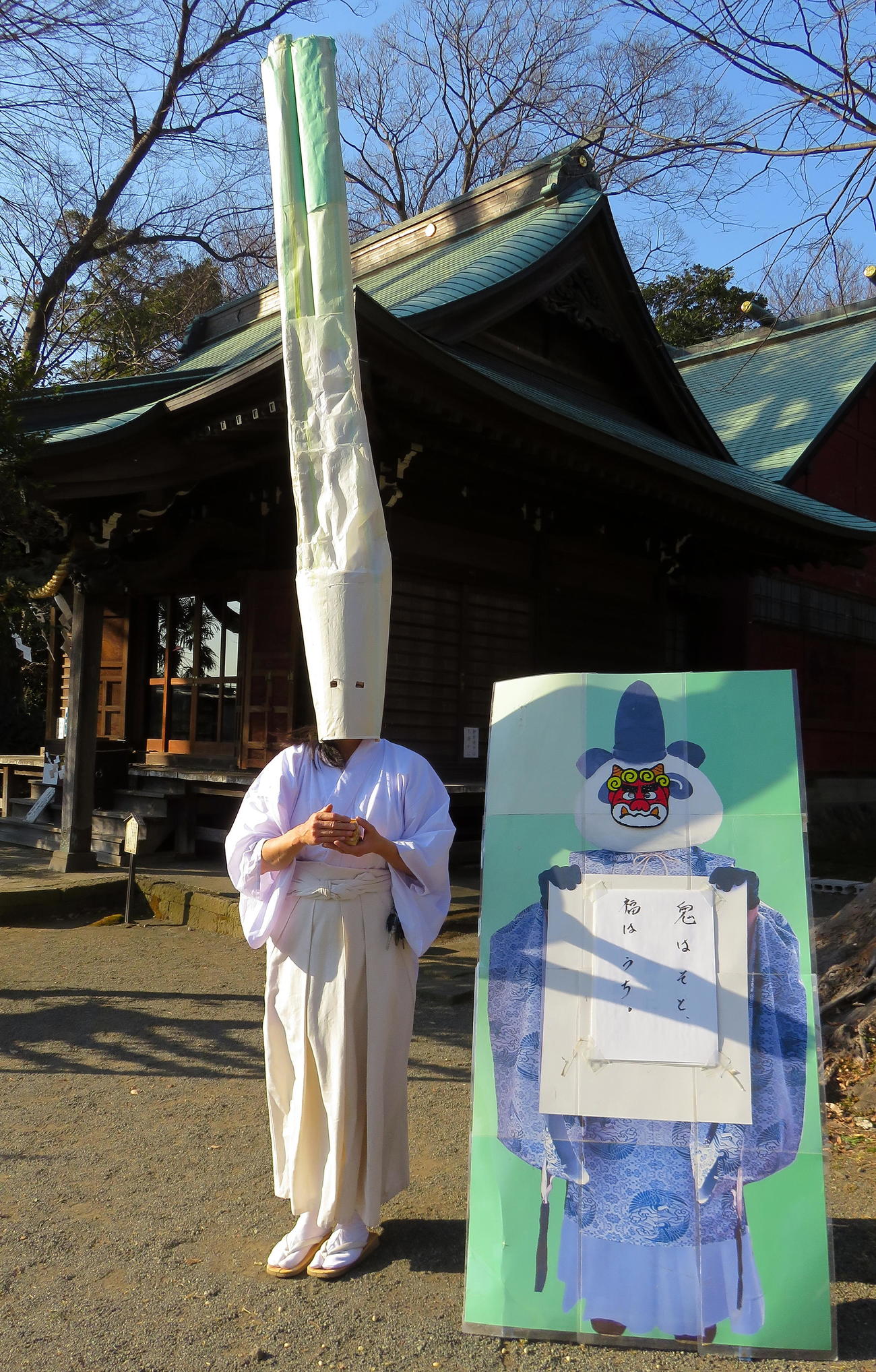 豆まき後に鬼役のパンダ宮司パネルと記念撮影する有鹿神社のネギ禰宜（撮影・鎌田直秀）