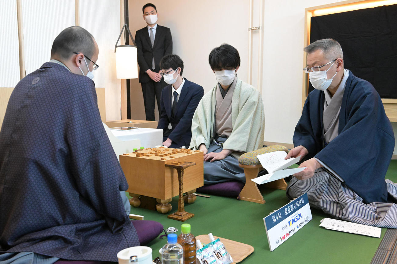 第71期ALSOK杯王将戦7番勝負第4局2日目。立会の中村修九段（右端）が示した封じ手を見る渡辺明王将（左）と藤井聡太竜王（右から2人目）（代表撮影）