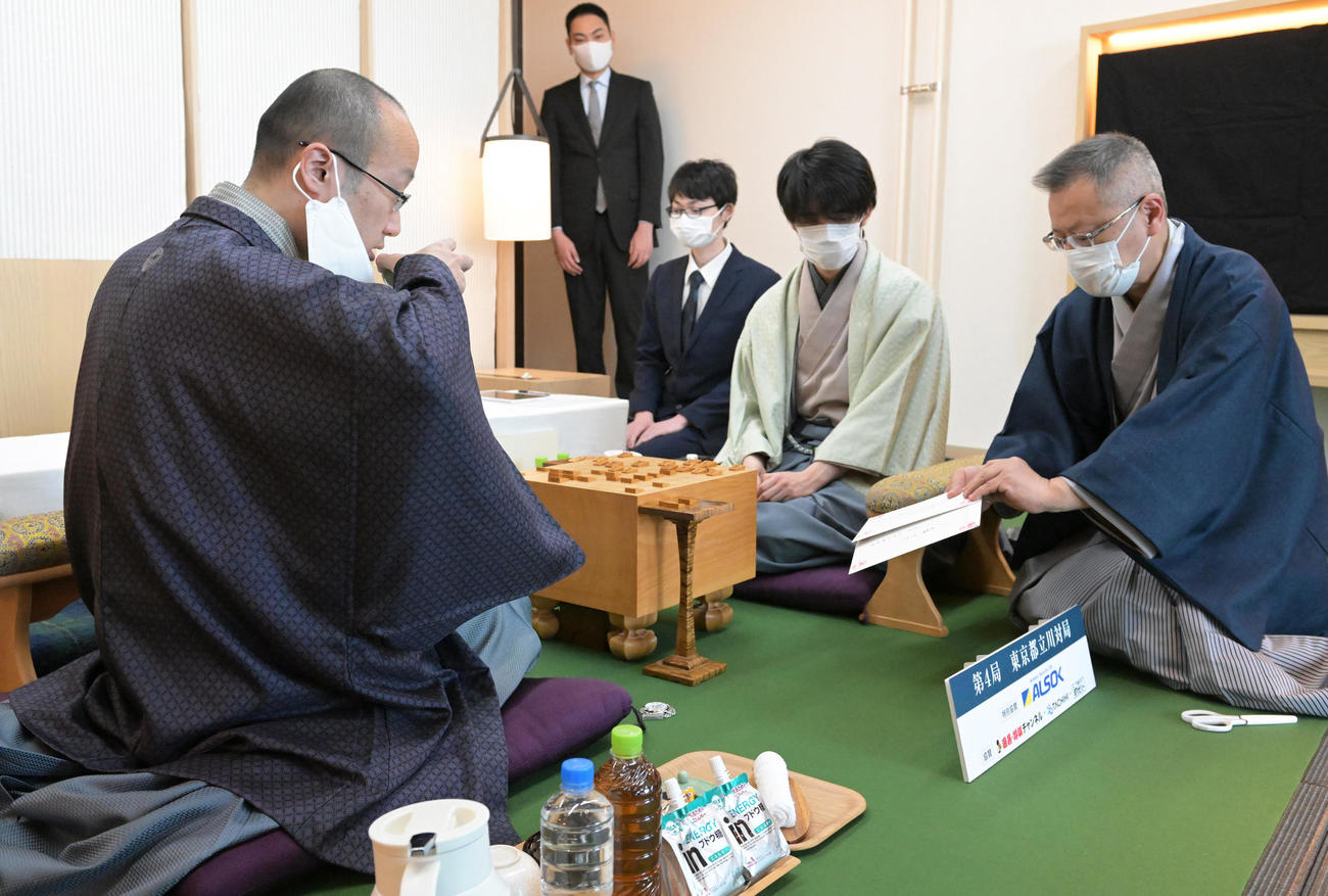 第71期ALSOK杯王将戦7番勝負第4局2日目。立会の中村修九段（右端）が示した、封じ手が入った封を見る渡辺明王将（左）。右から2人目は藤井聡太竜王（代表撮影）