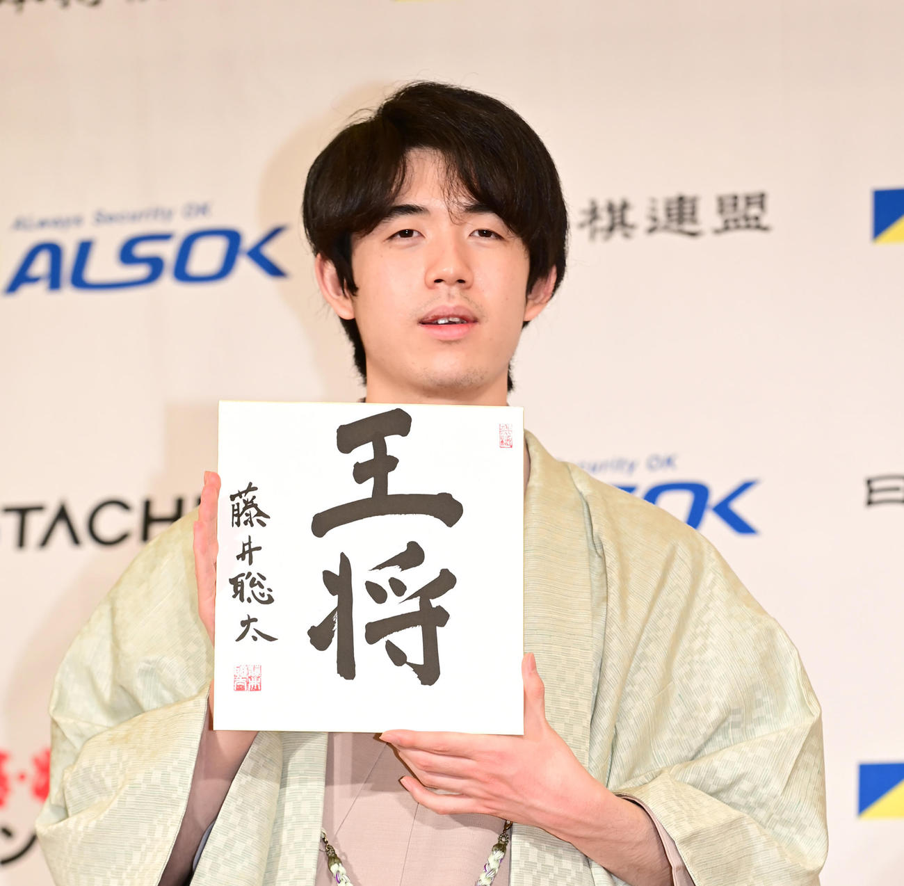 王将戦を4戦全勝で制し史上最年少で5冠を達成した藤井王将は「王将」の揮毫（きごう）を手に笑顔を見せる（撮影・小沢裕）