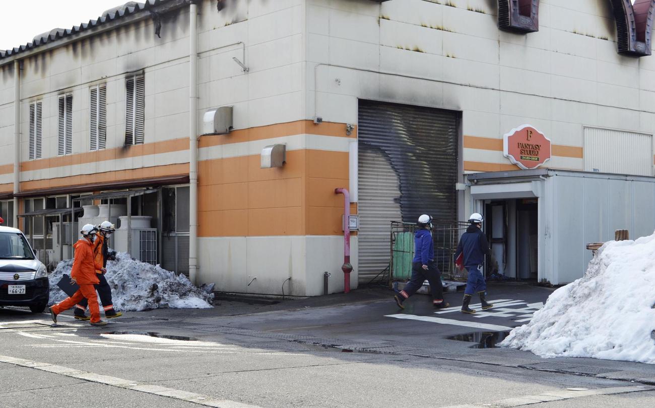 火災があった「三幸製菓」に入る捜査員ら（共同）