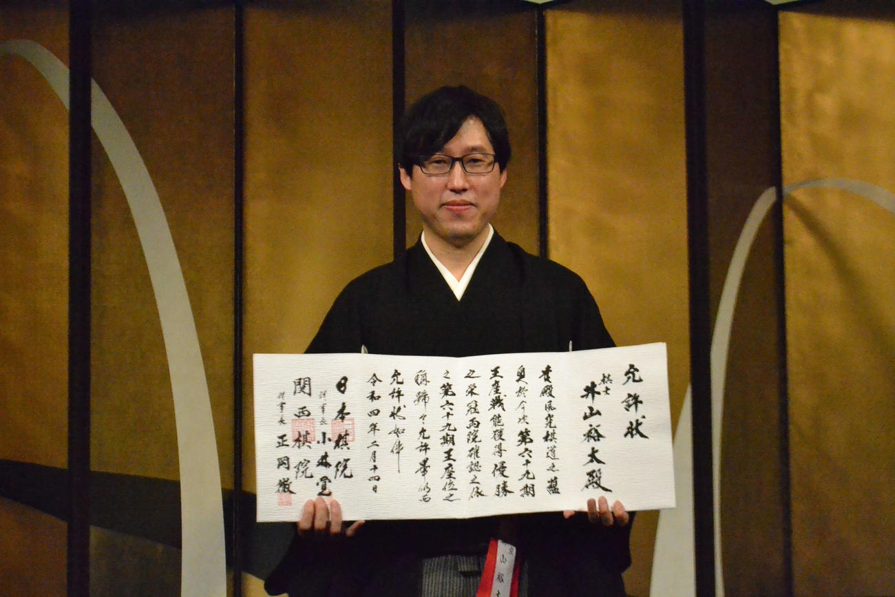 就位式で允許（いんきょ）状を手にする井山裕太王座