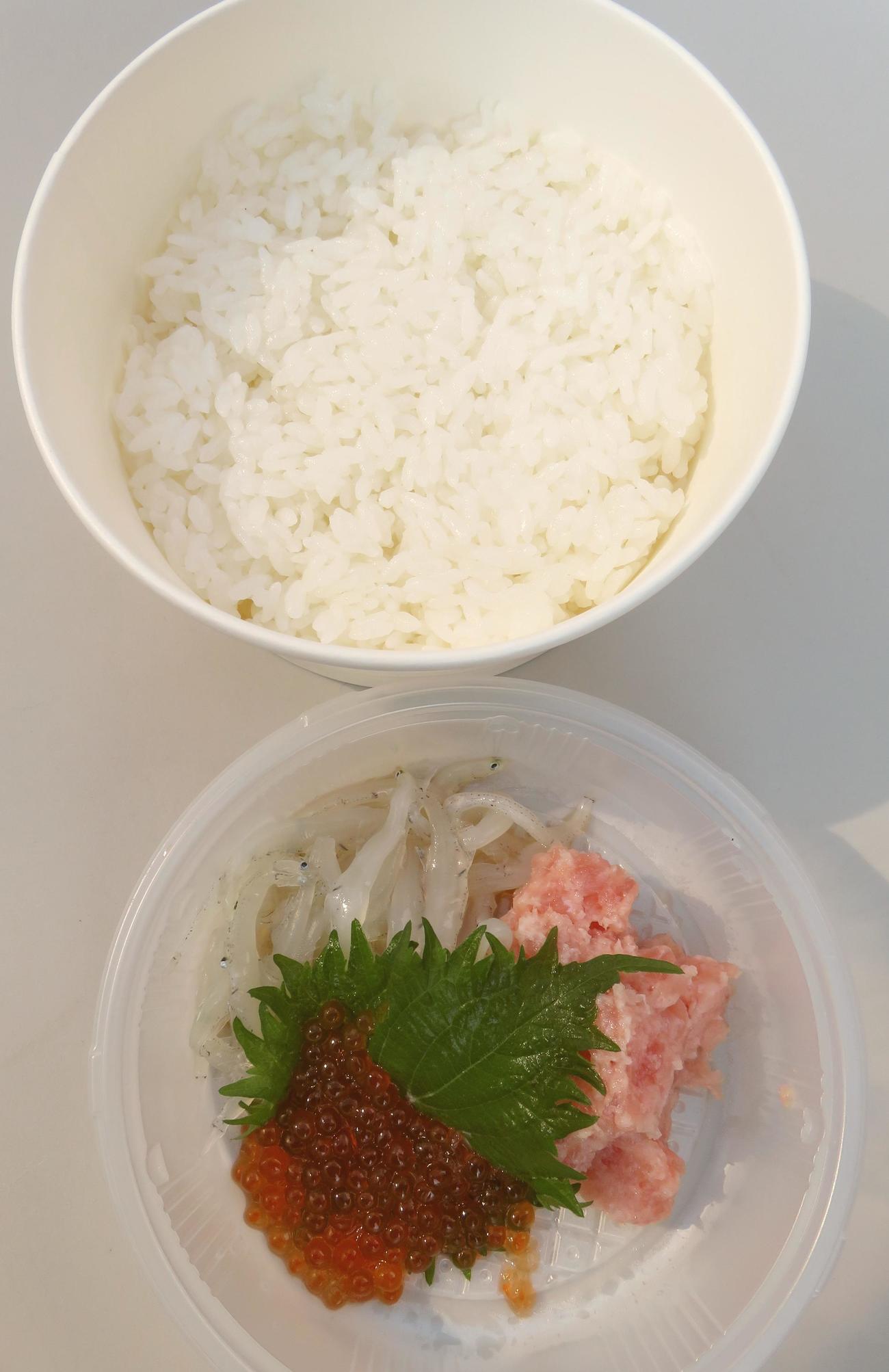 ご飯と刺し身は別々の容器で重ねられている。写真は新妻秀規復興庁副大臣が試食したシラウオ、ネギトロ、イクラの3食盛り（撮影・寺沢卓）
