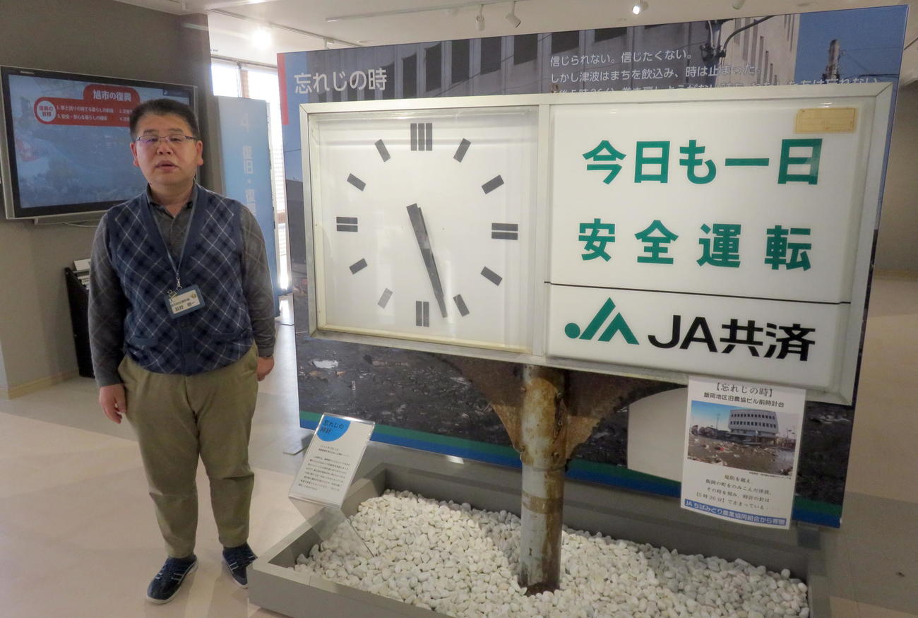 第3波に襲われた時刻で止まっているJAちばみどり飯岡支所の時計などが展示されている旭市防災資料館で説明員を務める辰野淳一さん（撮影・鎌田直秀）