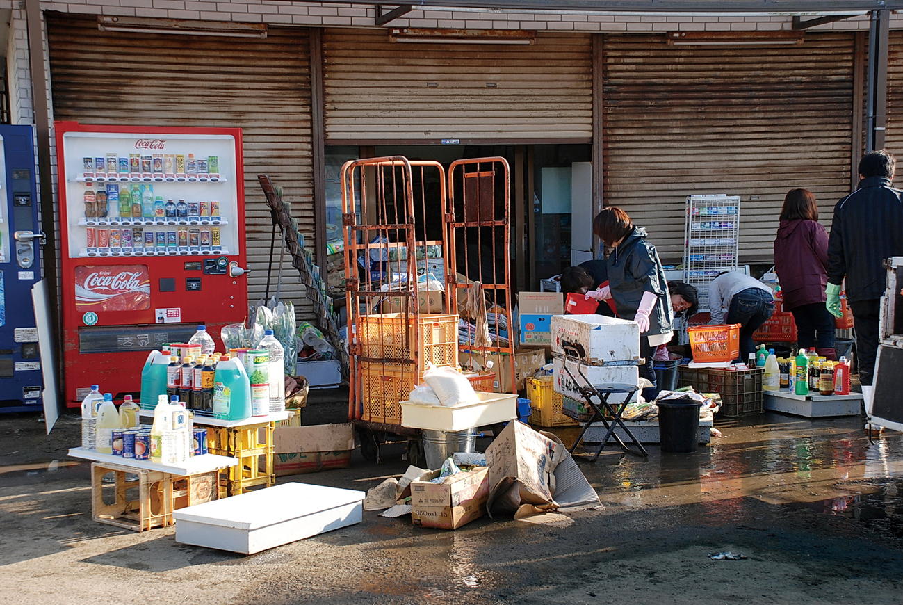 2011年3月12日、床上浸水した商店で商品などを片づける市民たち（旭市提供）