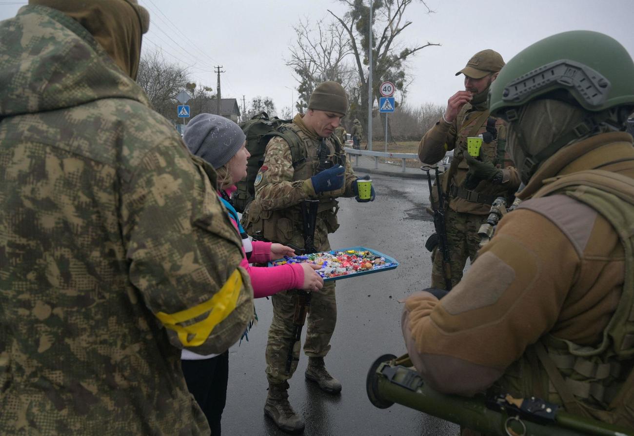 ウクライナ軍兵士に菓子を配る女性＝2日、キエフ郊外（ロイター＝共同）