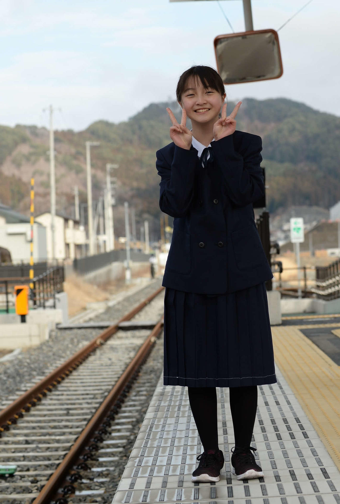 7年生になる制服を着て、大槌駅でポーズを決める小松倫子さん＝2020年2月22日