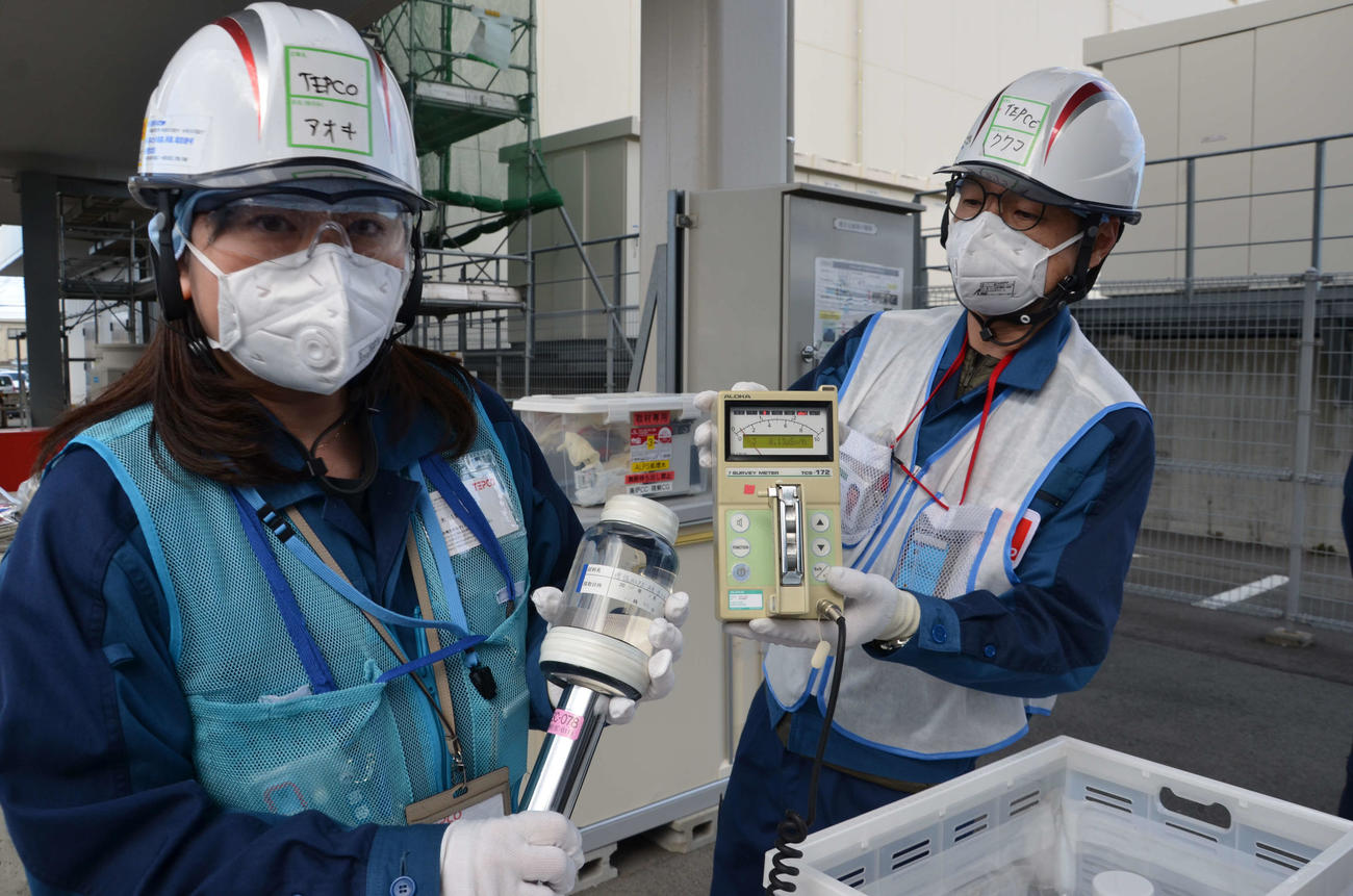 ALPS（アルプス＝多核種除去設備）処理水の放射線量を測定する東電の社員（日本記者クラブ代表撮影）