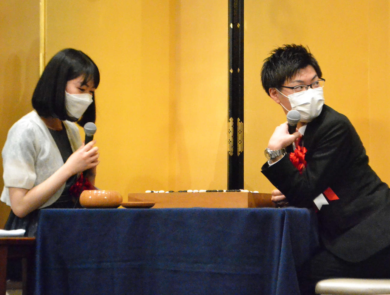 祝賀会の中で後輩とともに記念対局を行った関航太郎天元（右）と上野愛咲美女流棋聖（左）
