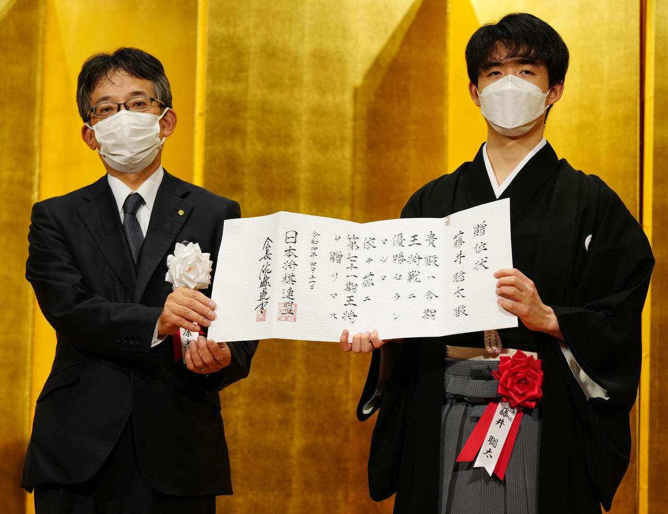 王将就位式で贈位状を手にする藤井聡太5冠（右）。左は日本将棋連盟佐藤康光会長（撮影・江口和貴）
