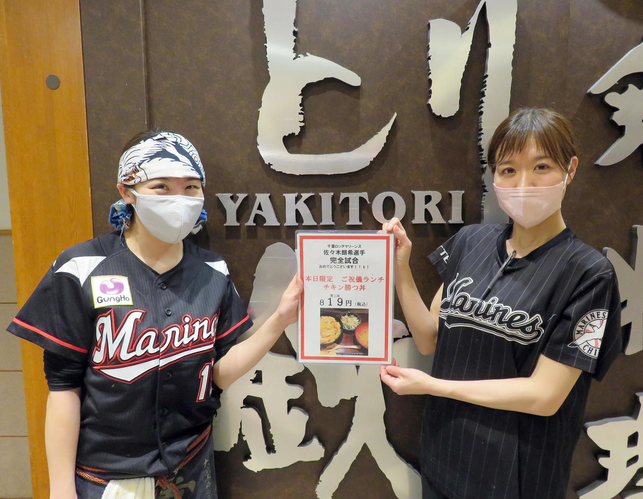 千葉ロッテ佐々木朗希投手の完全試合ご祝儀ランチ「チキン勝つ丼」メニュー表を手にする「とり鉄プレナ幕張店」吉岡真優店長（左）と佐々木のユニホームを着る従業員の岩本絢さん（撮影・鎌田直秀）