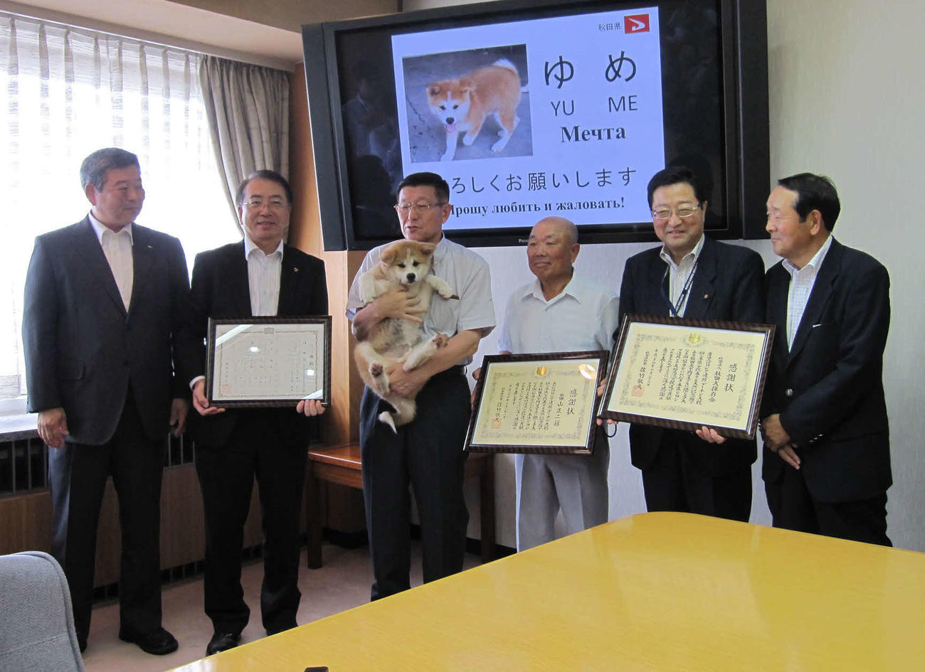 秋田犬「ゆめ」を抱える佐竹敬久秋田県知事（左から3人目）と飼い主の畠山正二さん（同4人目）