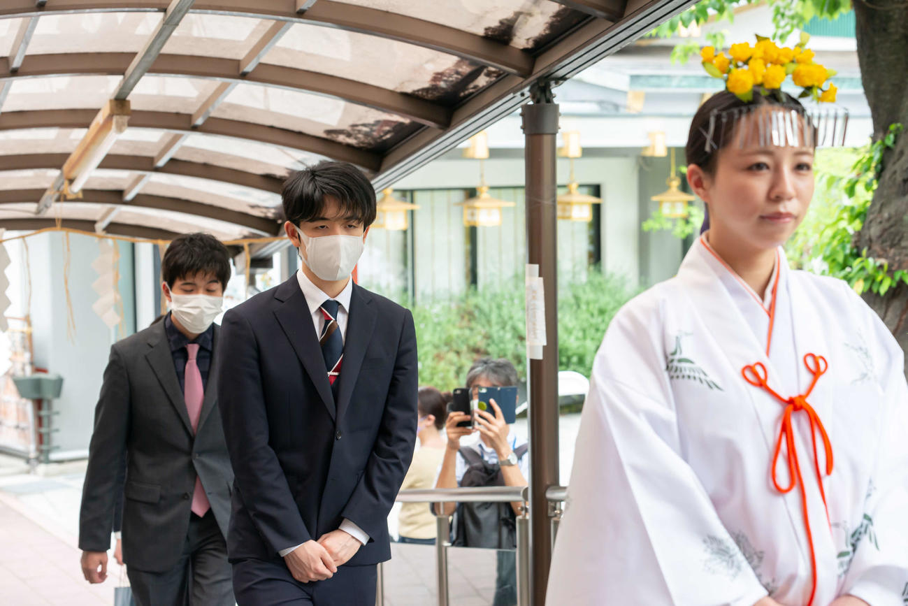 神田明神での対局の成功祈願に向かう藤井聡太叡王（中央）と出口若武六段（左、日本将棋連盟提供）