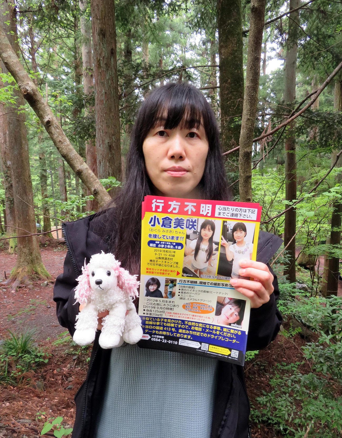 小倉美咲さん愛用の犬のぬいぐるみと捜索用チラシを手に行方不明になったキャンプ場を訪れた母とも子さん（撮影・鎌田直秀）
