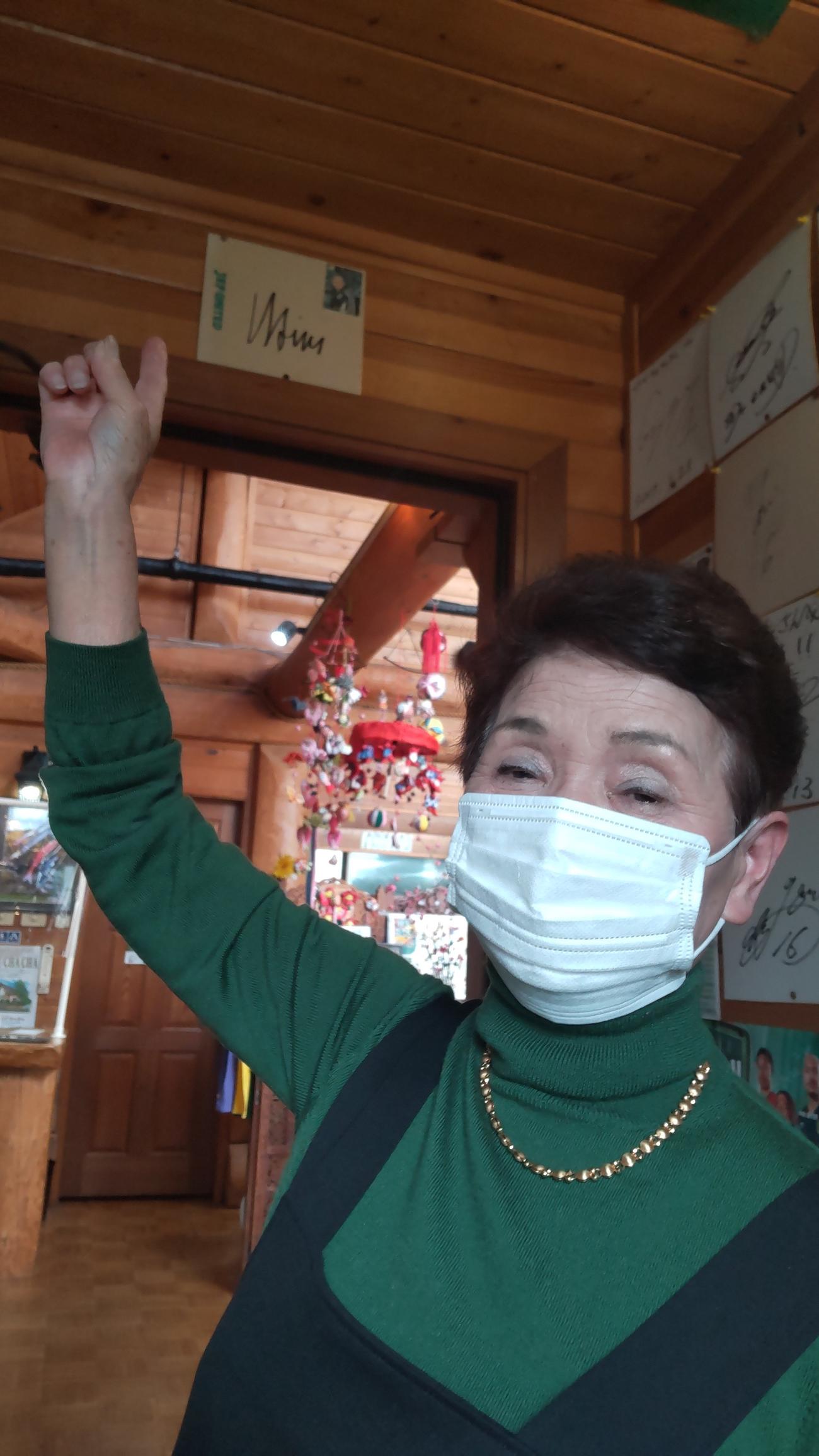 店の出入り口のオシム氏のサインを指さす「ログチャチャ」の高石三枝子さん（撮影・寺沢卓）