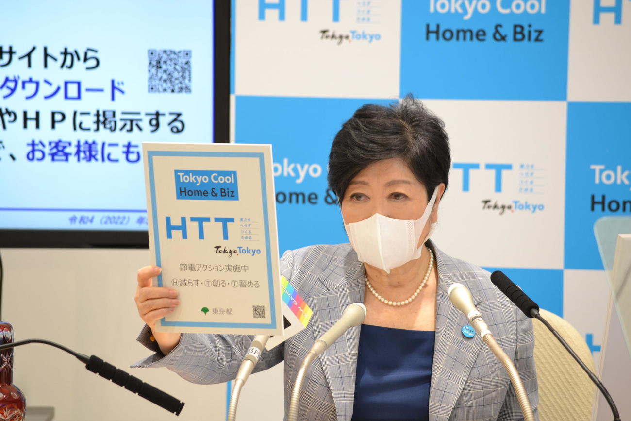 定例会見で節電を呼びかける「HTT」のボードを掲げる小池百合子都知事（東京都提供）