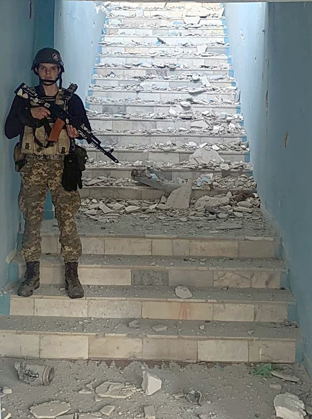 爆撃を受けたとみられる建物の階段に立つイゴールさん（佐々木清志さん提供）
