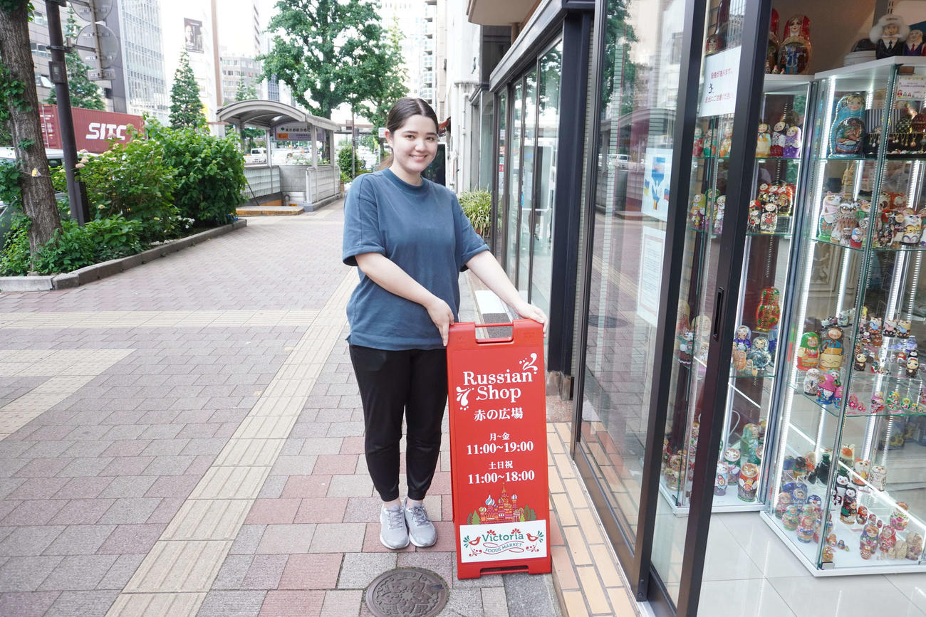 修繕された看板の横に立つ宮部リナさん（撮影・沢田直人）