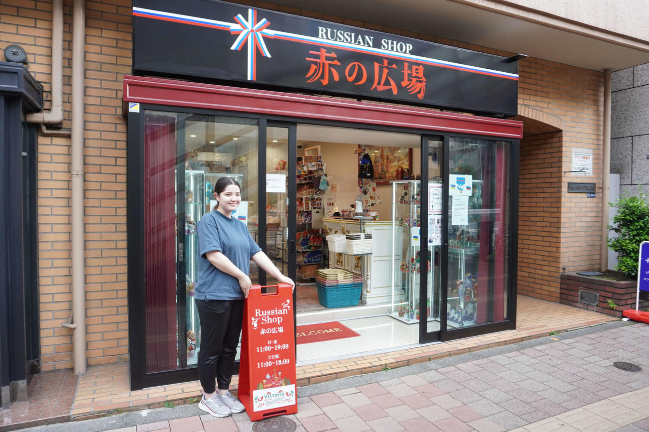 修繕された看板の横に立つ宮部リナさん（撮影・沢田直人）