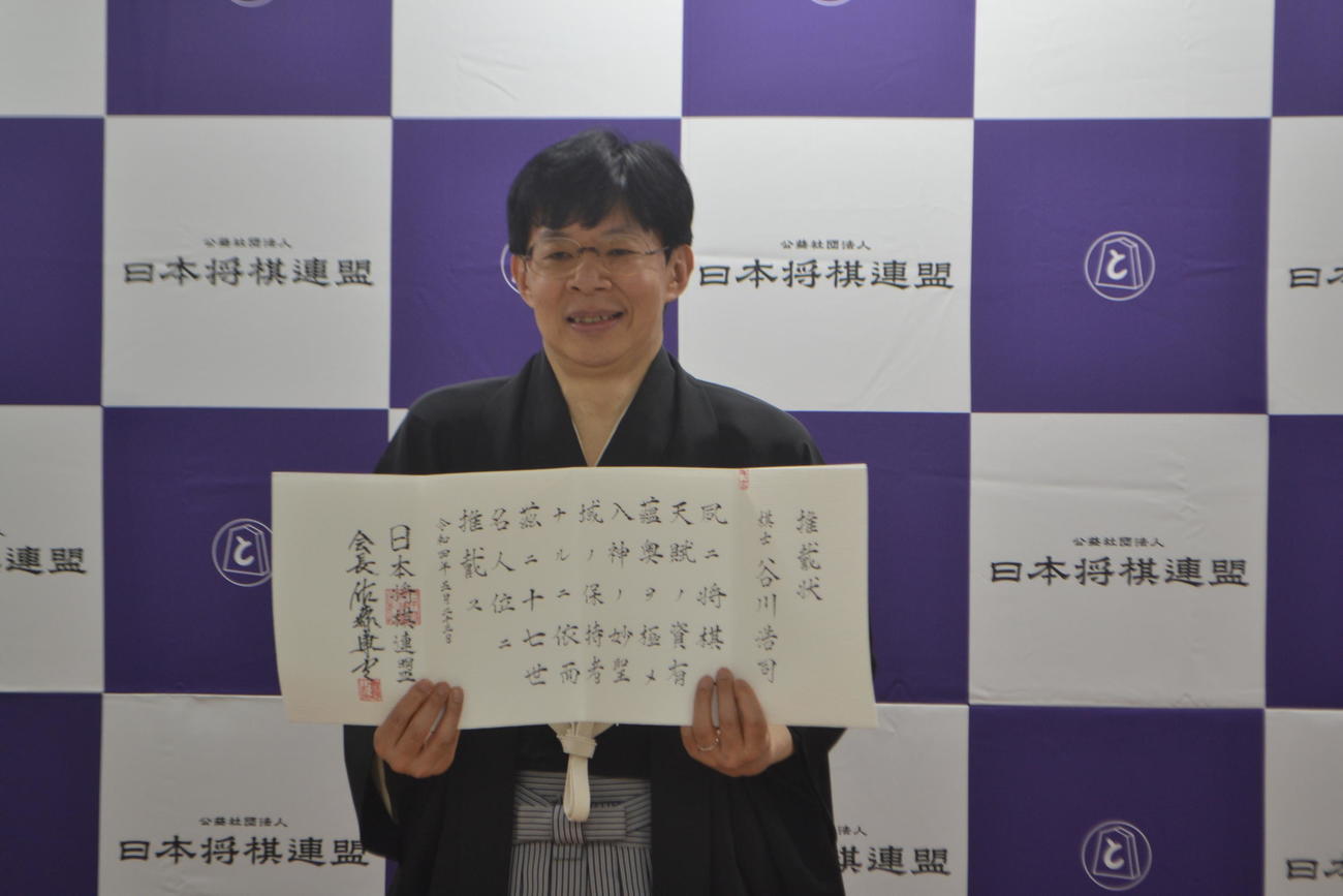 十七世名人の推戴（すいたい）状を手にする谷川浩司九段