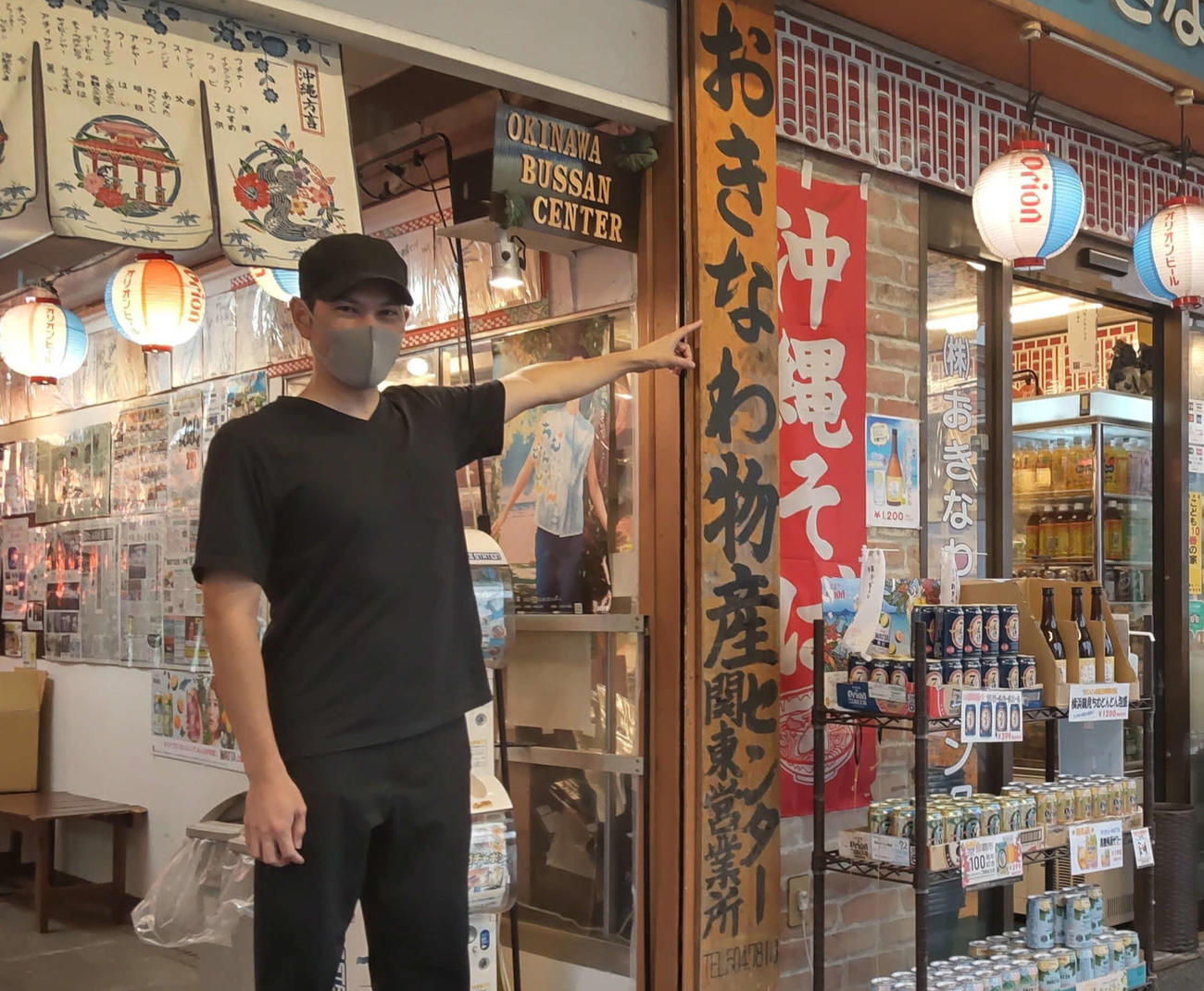 おきなわ物産センターの最初の看板を指さす下里優太社長。「この“な”は、間違いなく父の筆跡」
