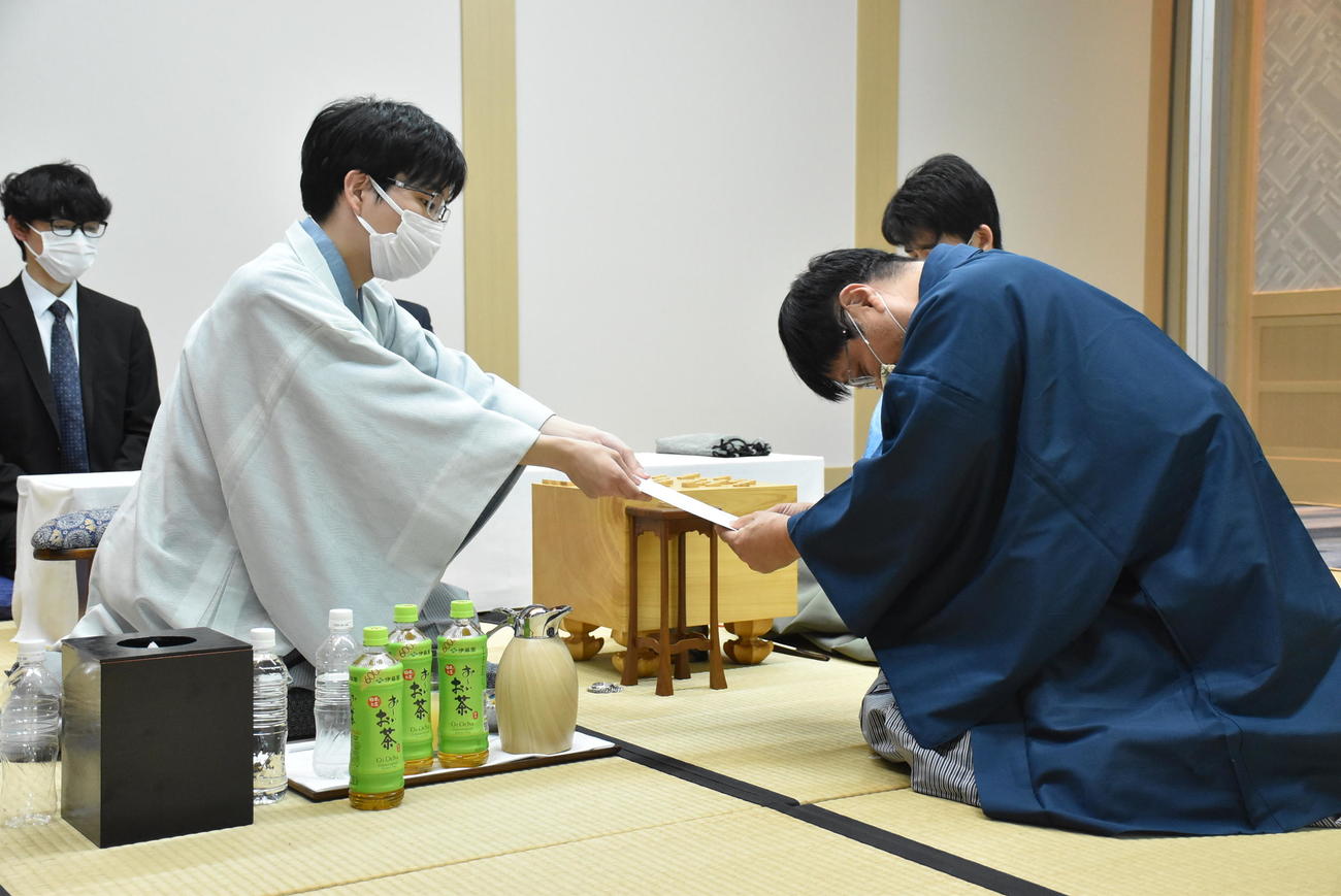 封じ手の封筒を立会人の小林健二九段（右）に手渡す豊島将之九段（日本将棋連盟提供）