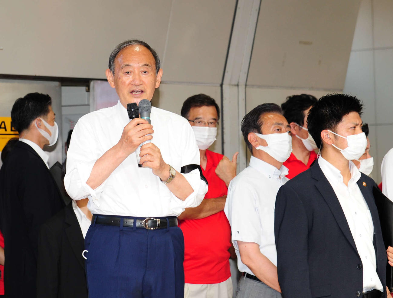 多くの警護に囲まれてあいさつする菅義偉前首相