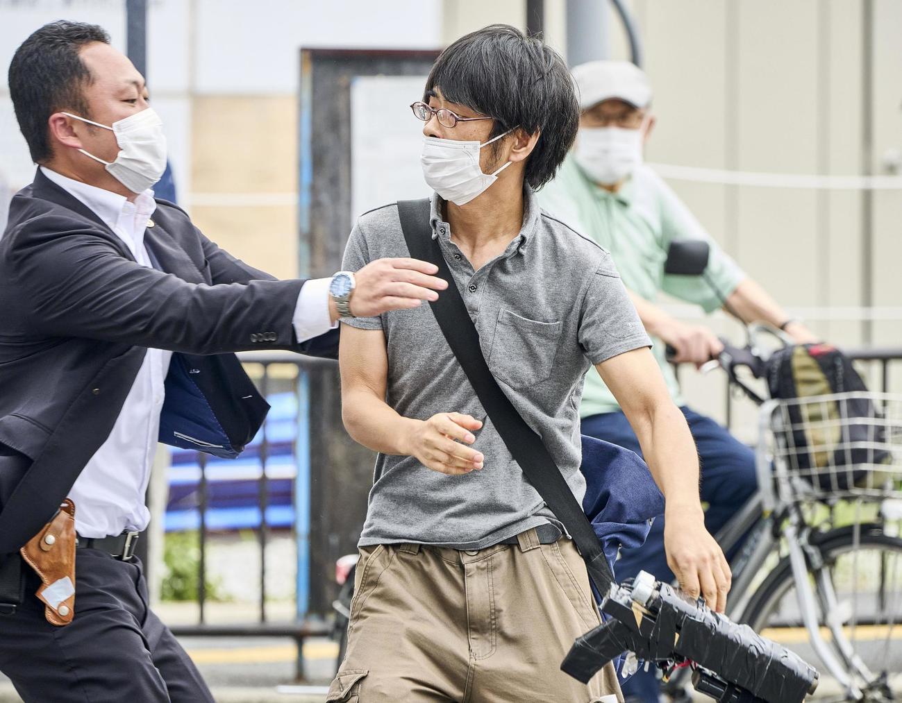 安倍元首相が銃撃された現場付近で取り押さえられる山上徹也容疑者。手には凶器となった銃とみられるものを持っていた（奈良新聞社提供）