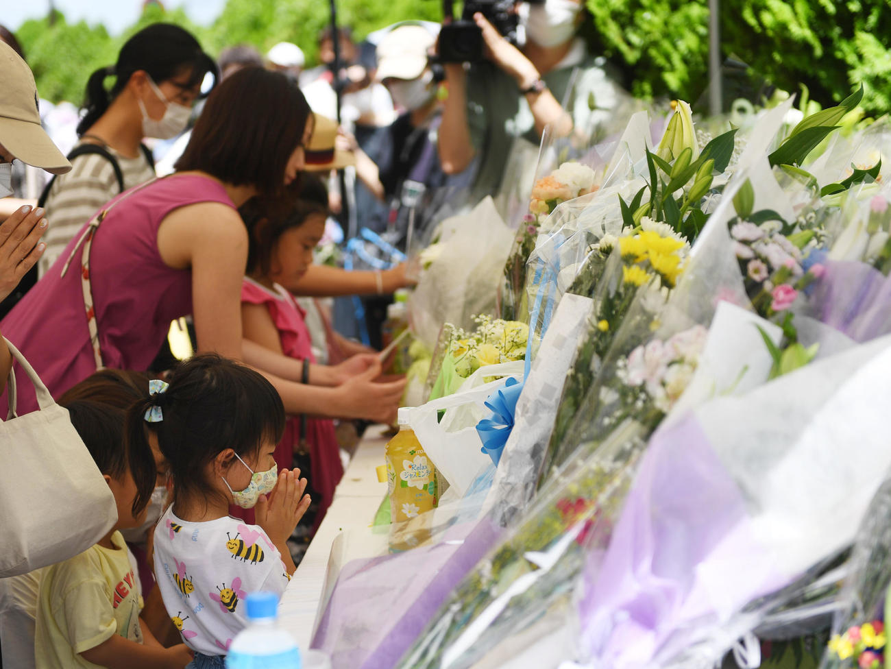 安倍晋三元首相が銃撃された現場付近に設置された献花台に花を供え手をあわすひとびと（撮影・前岡正明）