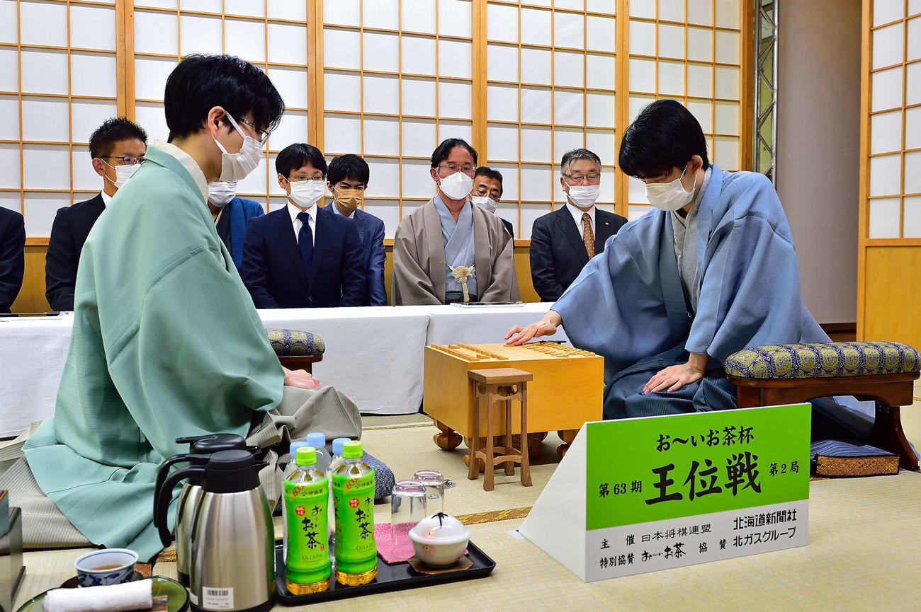 藤井聡太王位（右）の先手番で始まった「お～いお茶杯王位戦7番勝負第2局」。左は豊島将之九段（日本将棋連盟提供）