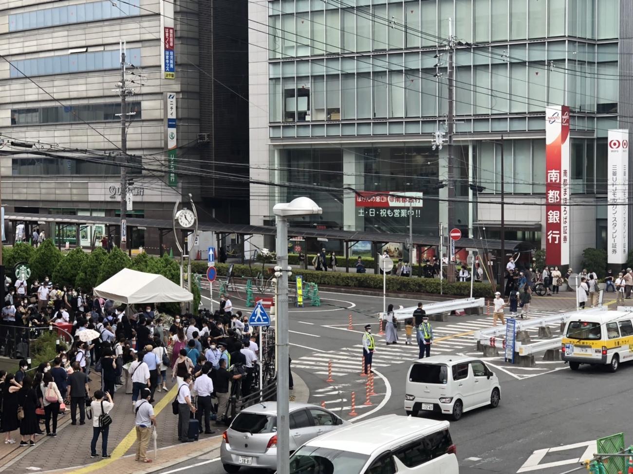 安倍晋三元首相が銃撃されてから1週間が過ぎた15日、事件現場（右）近くの献花台に集まる人たち（撮影・益子浩一）